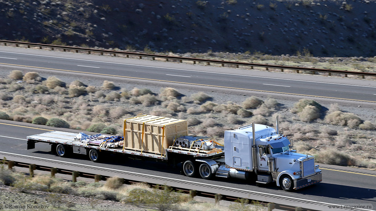 Американский грузовик движется по автодороги с гружённым тралом